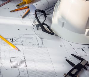Maintenance and engineering support services provided by COMS are here represented by the engineer's hard hat and detailed engineering drawings.